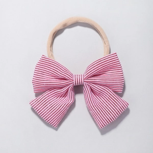 Detail of red and white striped bow baby headband with elastic nude nylon strap