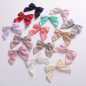 Flat lay of thirteen colorful cotton linen bow hair clips showing textured fabric detail