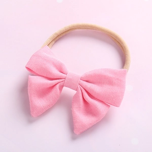 Détail du bandeau bébé en nylon souple avec un nœud rose clair texturé pour nouveau-né