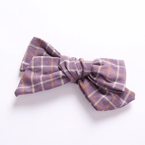 Macro view of purple checkered linen bow hair clip with detailed fabric texture