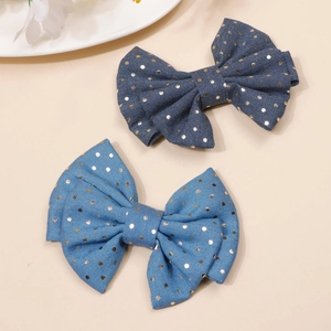 Detail of blue denim bow hair clips with gold polka dots on a minimalist background