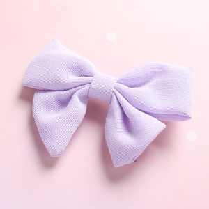 Detailed texture of a light purple linen bow hair clip for girls on a pink backdrop