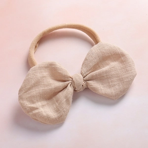 Soft nylon baby headband with a beige linen cotton bow on a soft purple background