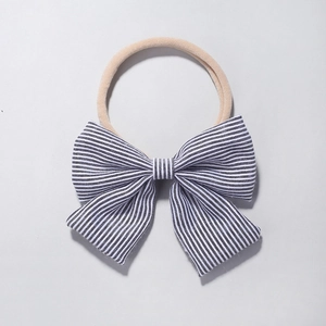 Detail of baby headband with a black and white striped bow on soft nylon fabric