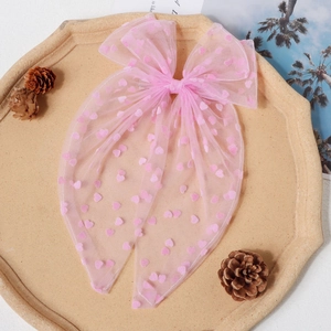 Détail du nœud de cheveux en tulle rose avec motifs cœur et longs rubans fluides