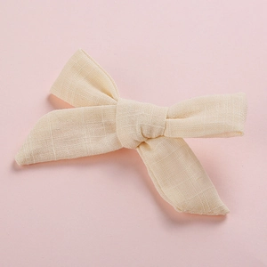 Macro detail of cream cotton bow hair clip showing high-quality woven texture