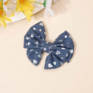 Detailed view of denim bow hair clip with silver sequin hearts and daisy accents