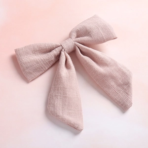 Detail shot of pale pink slub cotton bow hair clip with natural linen fabric texture