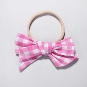 Detail of pink and white checkered bow headband made of soft cotton and nylon for babies