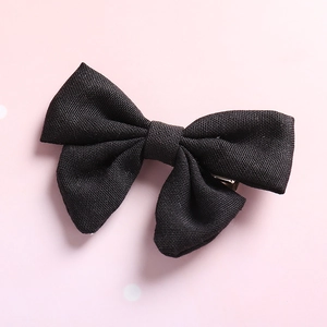 Detailed macro view of the black linen fabric texture and bow design of the girls hair clip