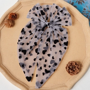 Détail d'un nœud à cheveux en résille blanche avec des motifs de cœurs noirs