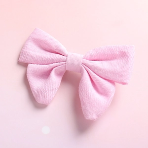 Detailed close-up showing the pink cotton linen texture of a classic girl's bow hair clip