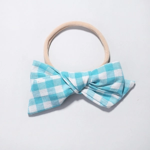 Detail of light blue gingham baby bow on a highly elastic beige nylon headband
