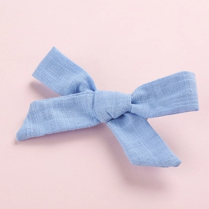 Detailed macro view of light blue linen bow hair clip showing fabric texture and neat knotting