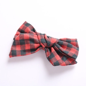 Detailed view of red and black plaid cotton bow hair clip with visible fabric texture