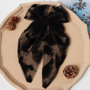 Détail d'un grand nœud à cheveux en résille noire avec texture plume sur plateau