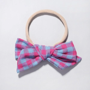 Detail of baby nylon headband featuring a pink and blue gingham plaid cotton bow accent