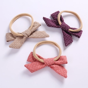 Detailed macro view of three linen baby bow headbands in coffee, purple, and coral pink