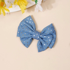 Detail of light blue denim hair clip with gold polka dots and a cute bow design