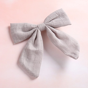 Close-up of light gray cotton linen bow hair clip showing textured fabric weave detail