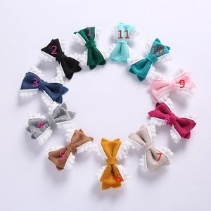 Vue de dessus de 11 barrettes nœuds en feutre coloré avec pompons blancs sur fond blanc