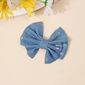 Close-up of denim bow hair clip with iridescent butterfly patterns and sequin details