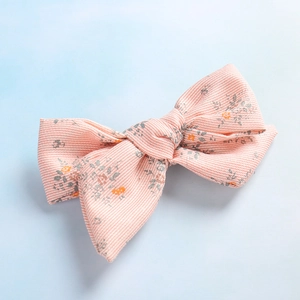 Détail de la pince à cheveux noeud en tissu à rayures roses et motif floral délicat
