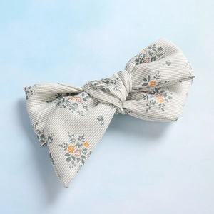 Détail de la pince à cheveux noeud floral avec motif de petites fleurs rétro sur tissu