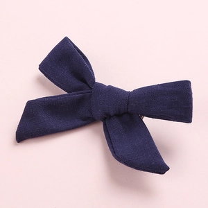 Detail showing the navy blue cotton bow hair clip texture on a pink background