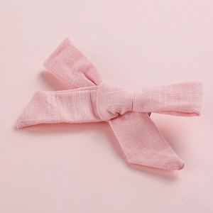 Detail view of pink cotton linen bow hair clip showing textured fabric and metal base