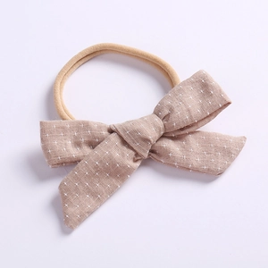 Detail of baby bow headband in beige cotton linen with delicate white floral pattern
