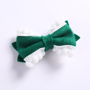 Vue détaillée du nœud à cheveux en feutre vert avec bordure pompon blanc pour enfant