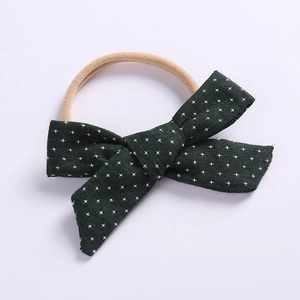 Detailed shot of dark green linen bow headband for babies with white floral pattern