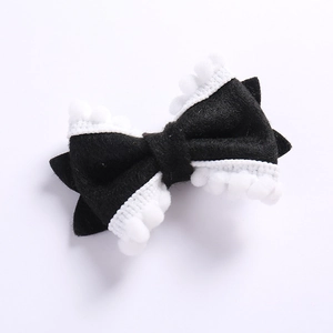 Détail d'un nœud papillon en feutre noir avec dentelle à pompons blancs pour fille