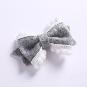 Détail d'un nœud papillon en feutre gris fait main avec bordure décorative à pompons blancs