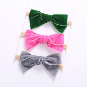 Detail von drei weichen Samt-Schleifen-Stirnbändern für Babys in Grün, Rosa und Grau