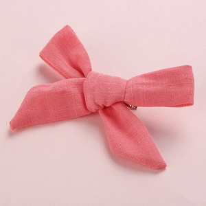 Close-up of a pink textured linen bow hair clip for girls with a solid color design