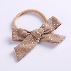 Close-up of brown cotton bow headband with white star prints on soft nylon elastic band