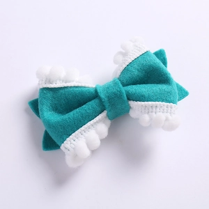 Détail d'une barrette nœud en feutre avec bordure en dentelle à pompons blancs