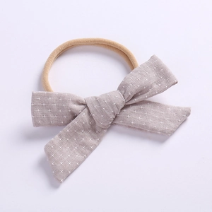 Detail of baby headband with dusty purple linen bow and white cross pattern on nylon band