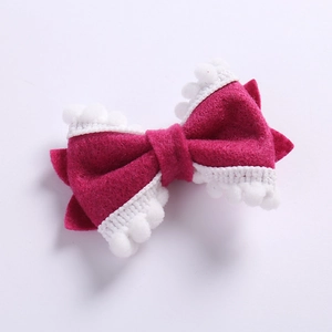 Vue détaillée du nœud en feutre magenta avec pompons blancs décoratifs pour filles