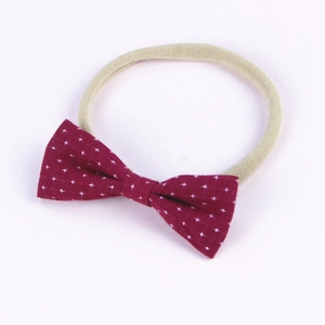 Detail of burgundy cotton baby headband with white star pattern and beige nylon band