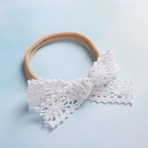 Dettaglio fascia per neonati in nylon con fiocco in pizzo bianco e trama elastica morbida