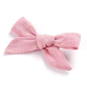Pink cotton linen bow hair clip for girls with natural textured fabric on white background