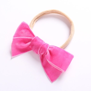 Makroaufnahme einer leuchtend rosa Samtschleife auf weichem Nylon-Stirnband für Babys