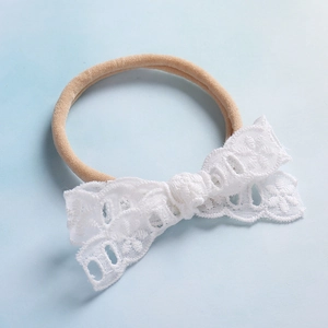 Dettaglio fascia per neonati in nylon con fiocco in pizzo floreale bianco su sfondo blu