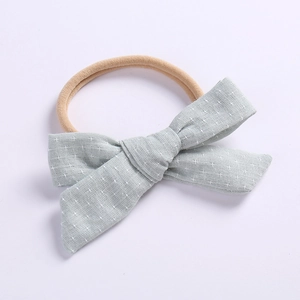 Detail of mint green linen baby bow headband with white cross pattern and nylon elastic band