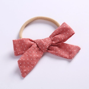 Detailed close-up of a dusty red linen baby headband with white cross patterns