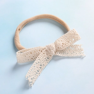 Dettaglio della fascia per neonati in nylon morbido con fiocco in pizzo beige