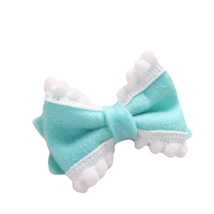 Barrette à cheveux nœud en feutre vert menthe avec pompons blancs sur fond blanc